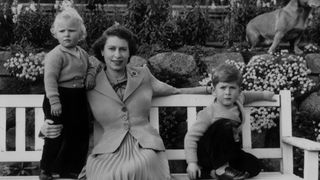 Queen Elizabeth sitting with her children, Charles and Anne and a royal corgi in the garden of Balmoral Castle