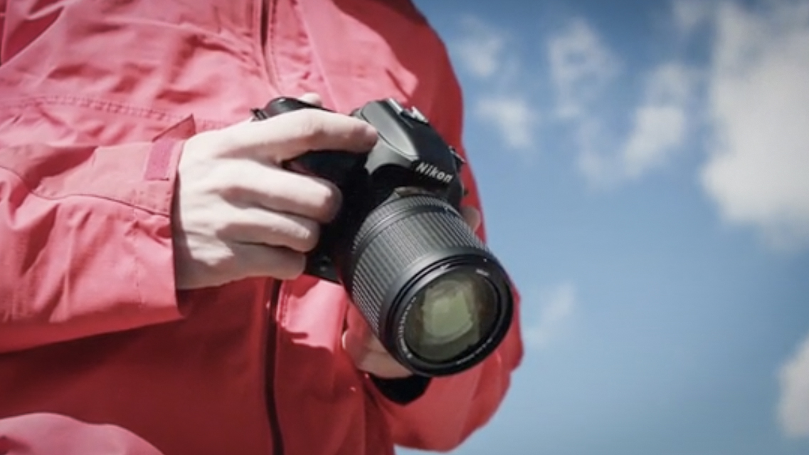 Photographer holding a Nikon D7500 outdoors
