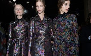 Three models wearing outfits from the same metallic fabric with butterfly print