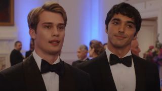 From left to right: Nicholas Galiztine as Henry standing next to Taylor Zakhar Perez as Alex both in tuxedos in Red, White & Royal Blue.