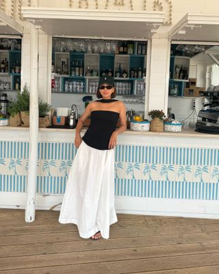 @aimeesong wearing black and white drop waist dress leaning against drink counter