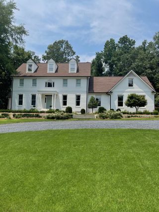 White house with large lawn and formal planting in front of house