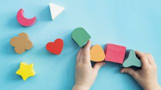 A toddler's hands play with some wooden blocks.