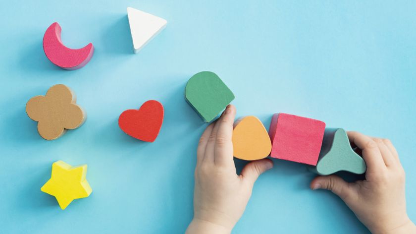 A toddler&#039;s hands play with some wooden blocks.