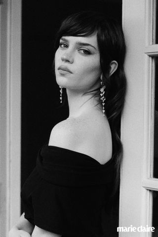 actress sophie thatcher poses in a doorway wearing a black off the shoulder dress