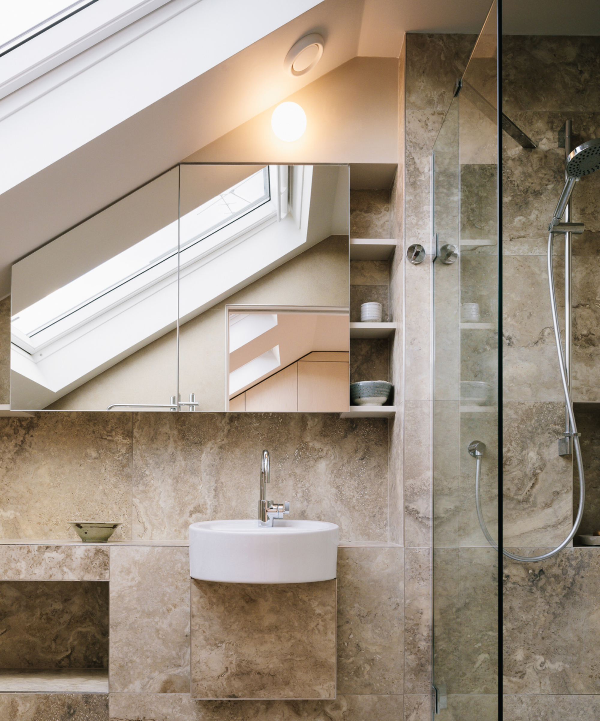 tile clad bathroom with rooflight, small sink, recessed and built in shelving, glass shower screen, mirrored cabinet and walk in shower