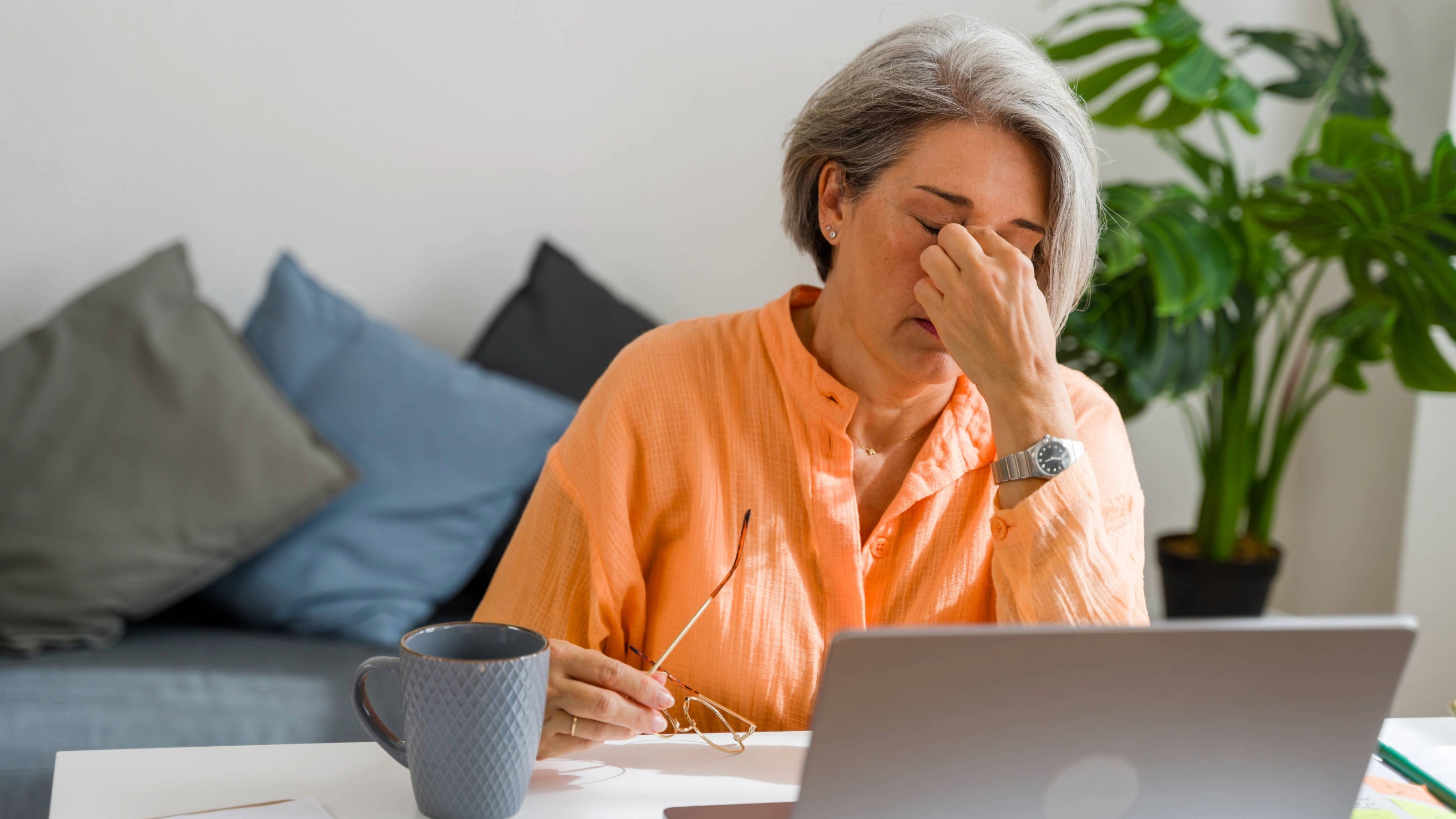 Stressed mature woman having headache while working on laptop