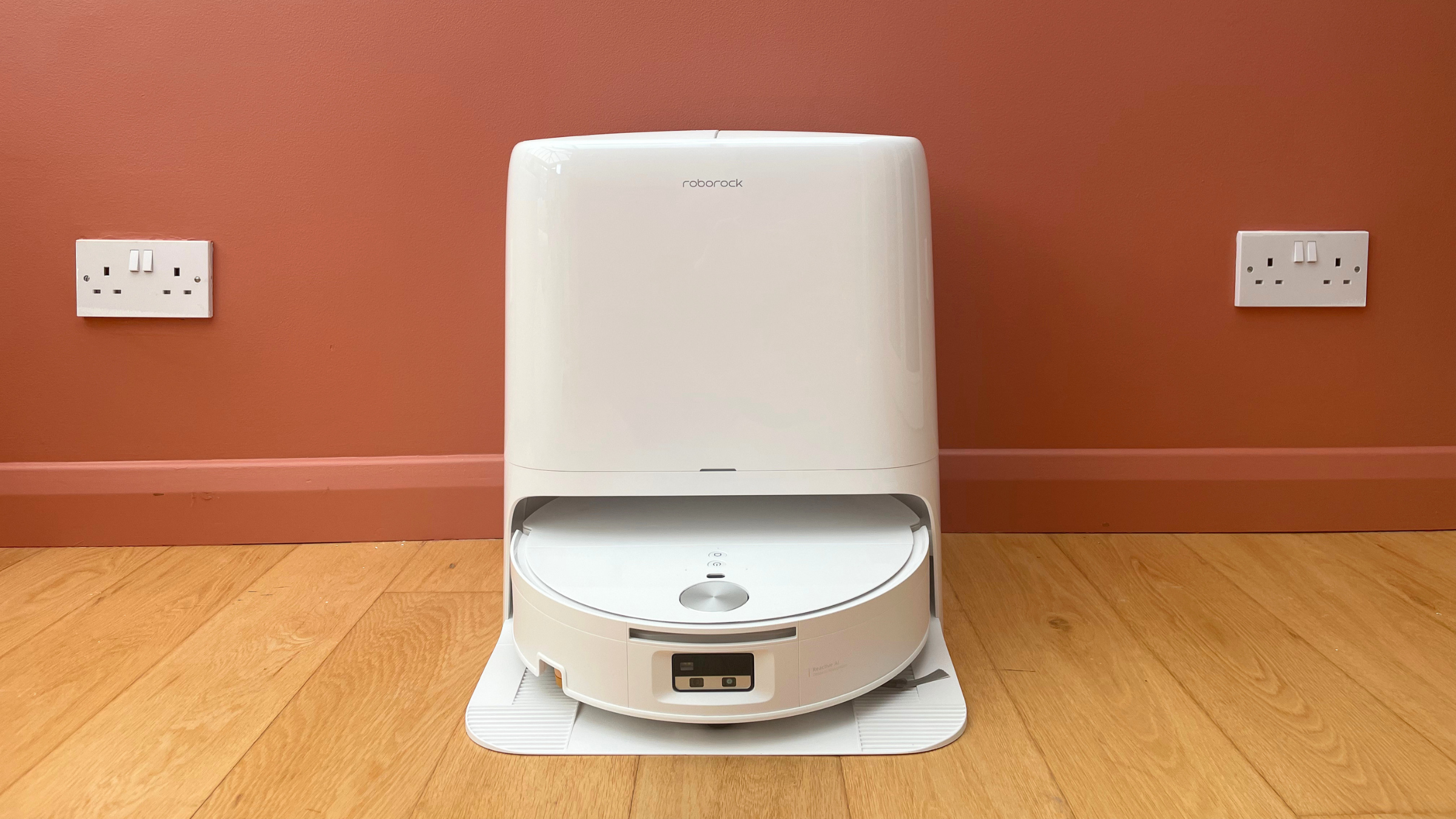 White Roborock Qrevo Edge 2 Flow Robot Vacuum sitting in front of a pink colour-drenched wall, on wooden flooring