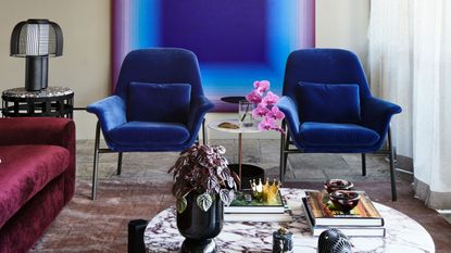 a living room with blue chairs and ombre wall art