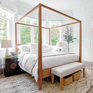 A white bedroom with a wooden four poster bed