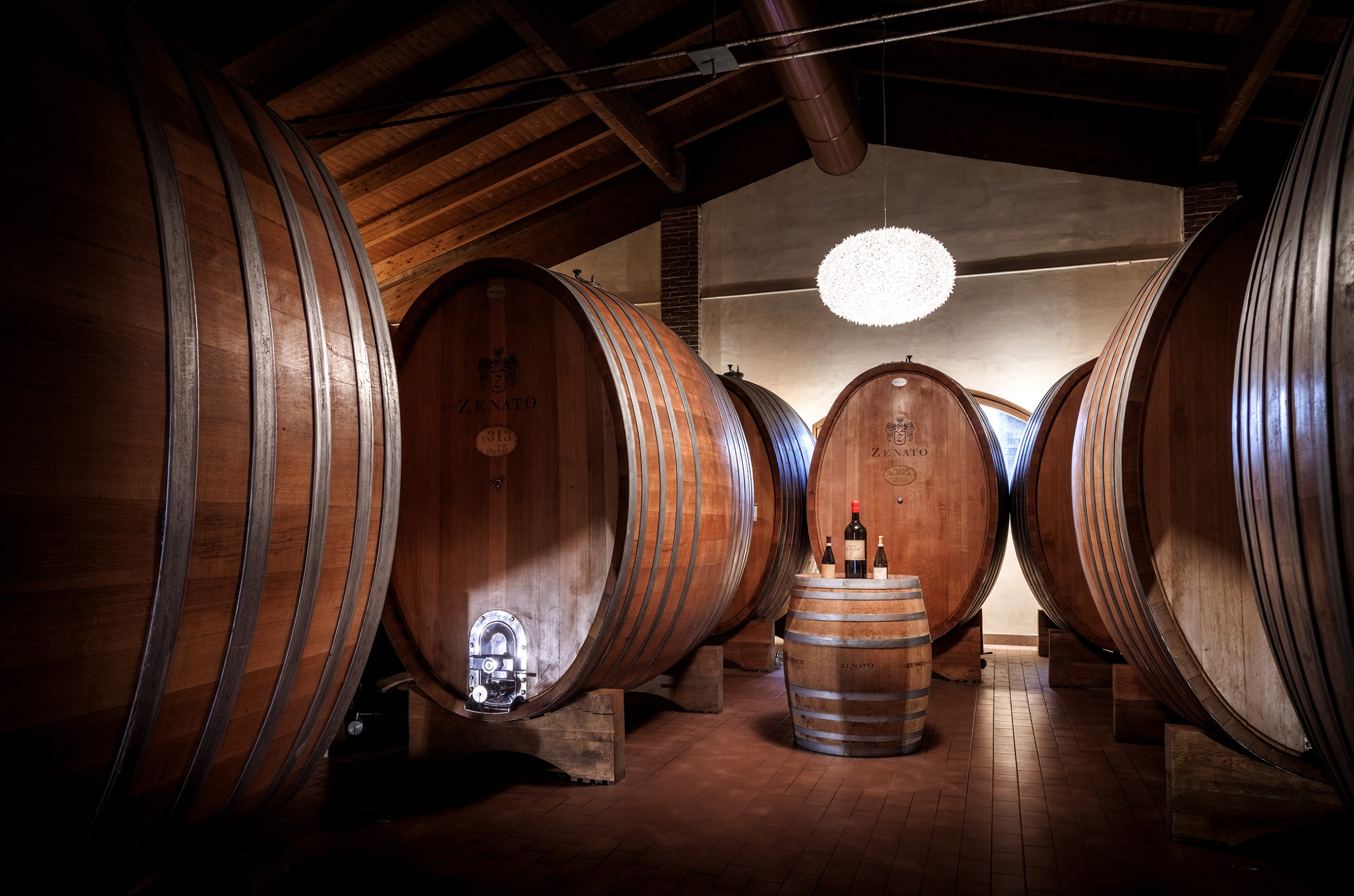 Room with large egg-shaped oak barrels, with an oak barrel in the centre of the room with a red wine bottle