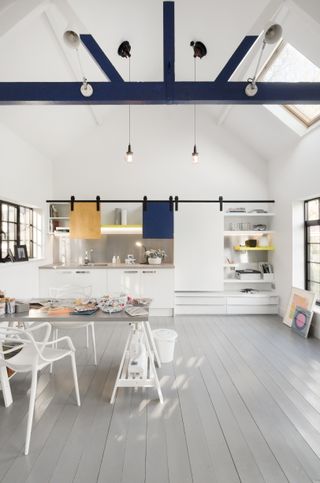 Kitchen cabinets using moveable colorful cabinet doors on a track with an architect's table as a dining table