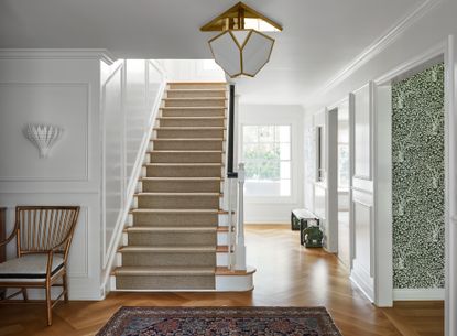 Entryway with staircase with rug at bottom.