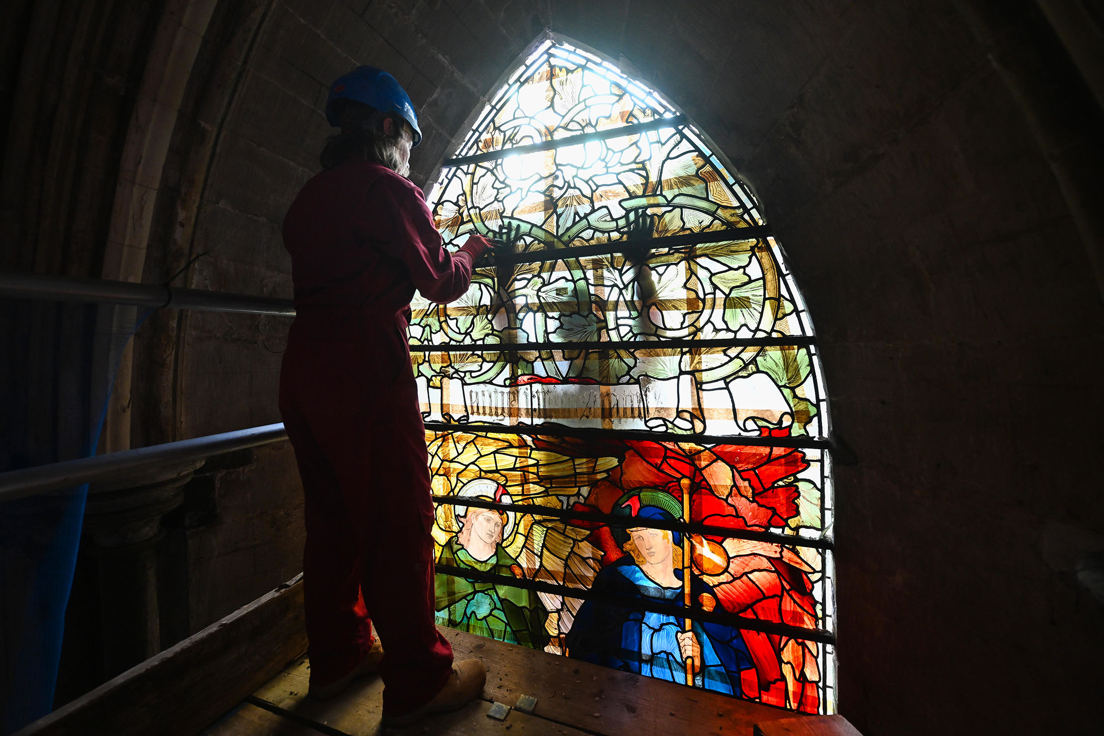 Glazier Kate Kersey prepares to remove the uppoer section of Angeli Ministrantes in the South Quire Aisle at Salisbury Cathedral.