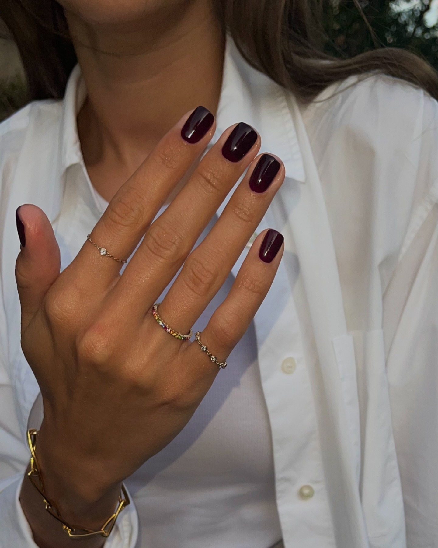 A photo of a woman with short black nails wearing a white shirt