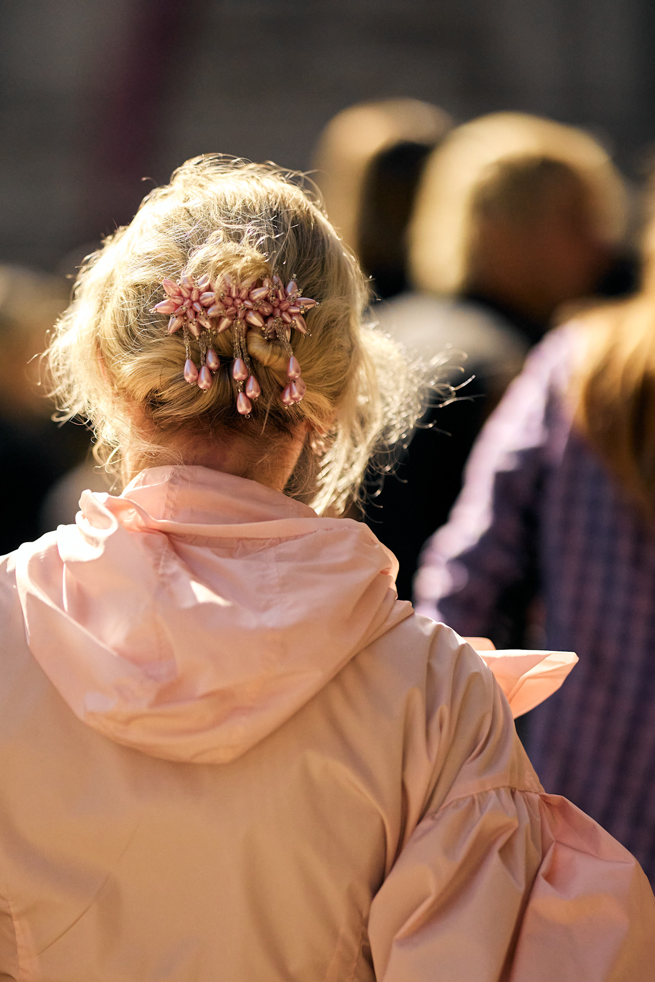 a blonde woman from the back with her hair held by pink flowers in a pink windbreaker