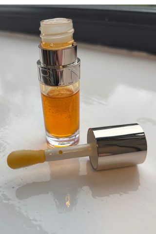 a shot of clarins lip oil with wand next to pot