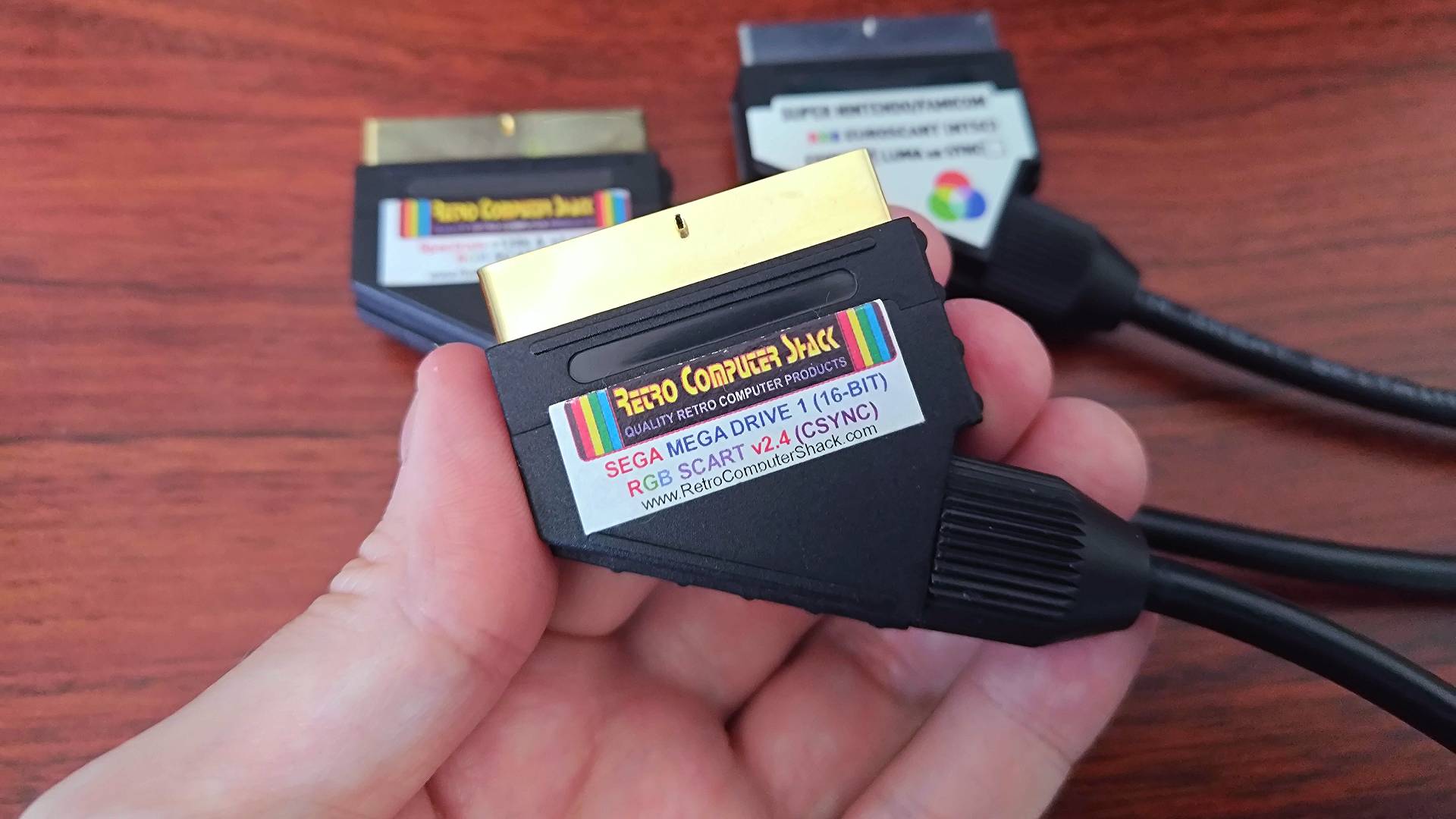 Hand holding Retro Computer Shack RGB SCART cable for Sega Mega Drive.