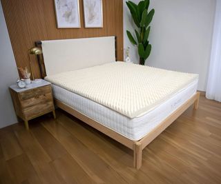 Turmerry Egg Crate Mattress Topper on a bed against brown wood panelling.