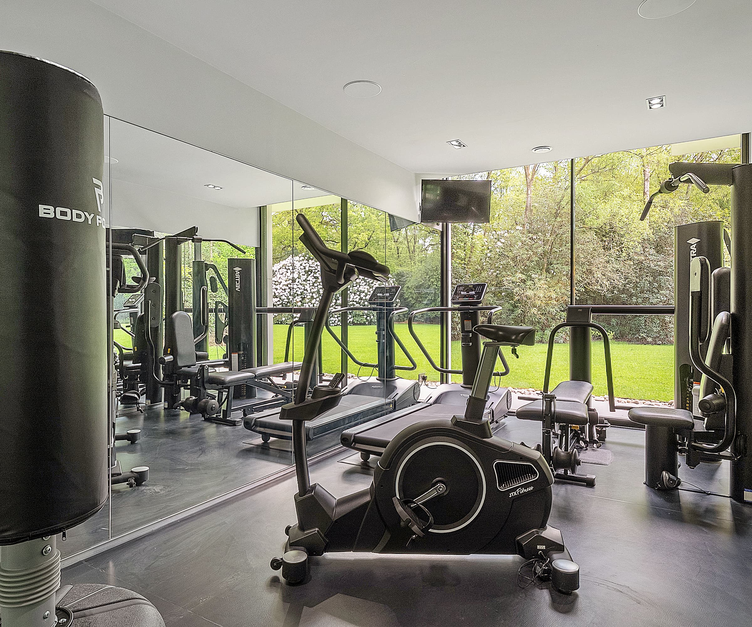 A home gym next to a bifold door with a cycling machine, punching bag and treadmill