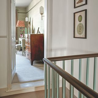 A landing next to the stairs looking into a room with wooden furniture inside