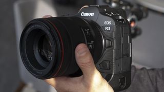 Two hands holding the Canon EOS R3 mirrorless camera