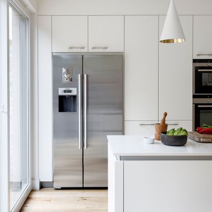 White kitchen cupboards with a large fridge freezer
