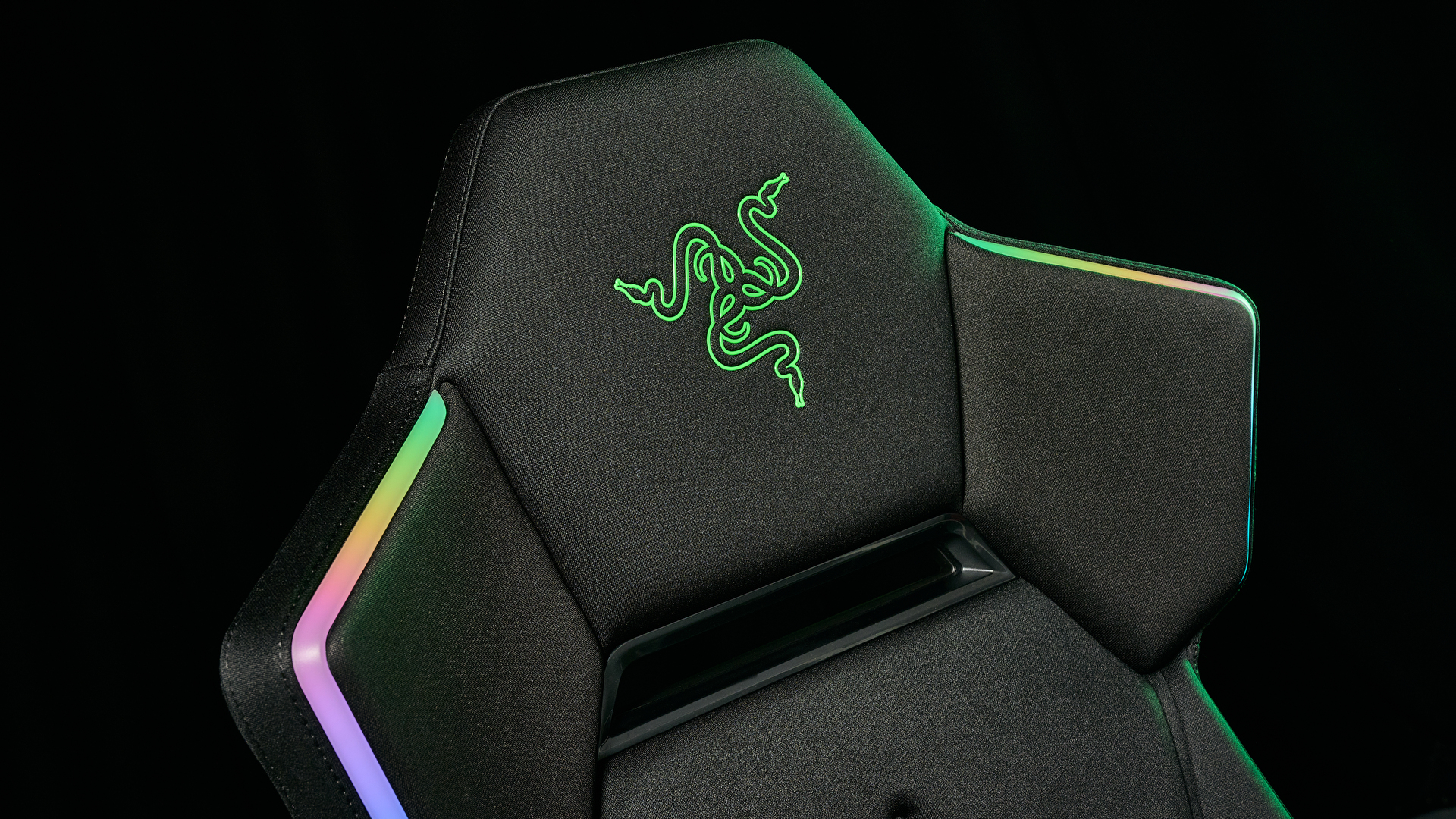 The Razer Soma Chroma headrest, with the RGB on, Razer logo showing and illuminated with a green glow