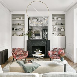 White living room with foxed glass mirror, sculptural ceiling light and two patterned armchairs
