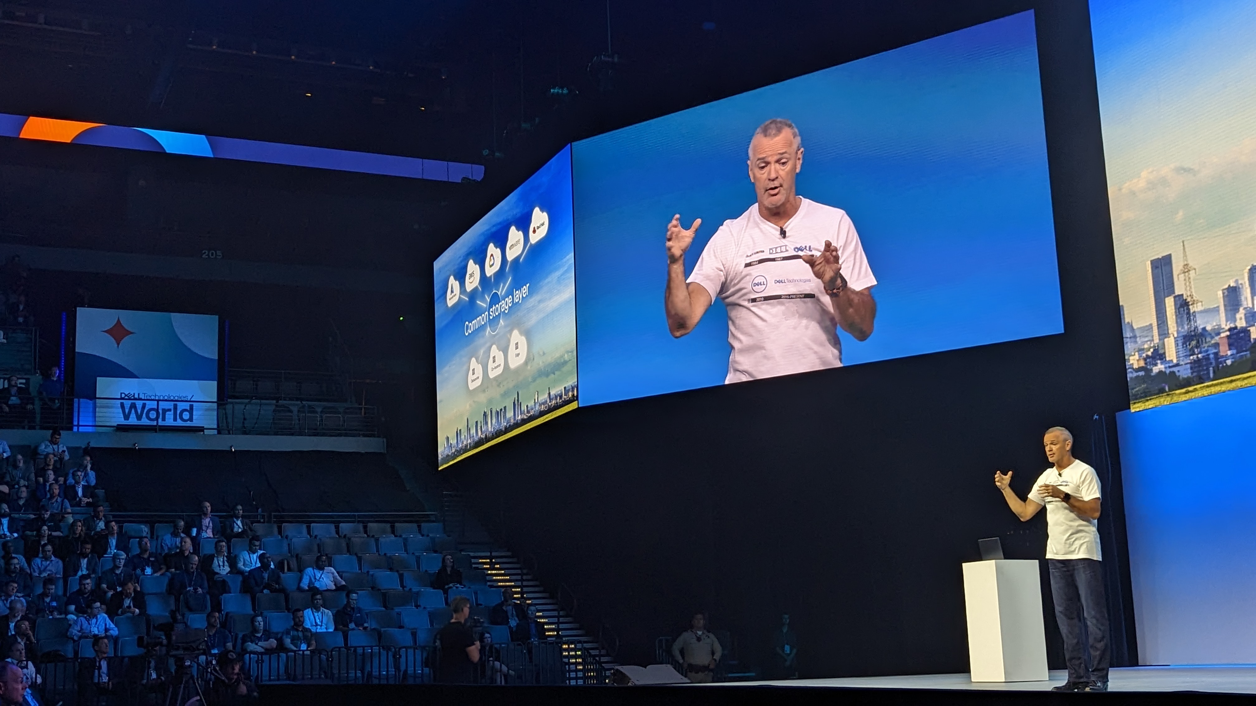 Dell's Jeff Clarke standing on stage, gesturing as a cloud diagram is shown on a screen above him.