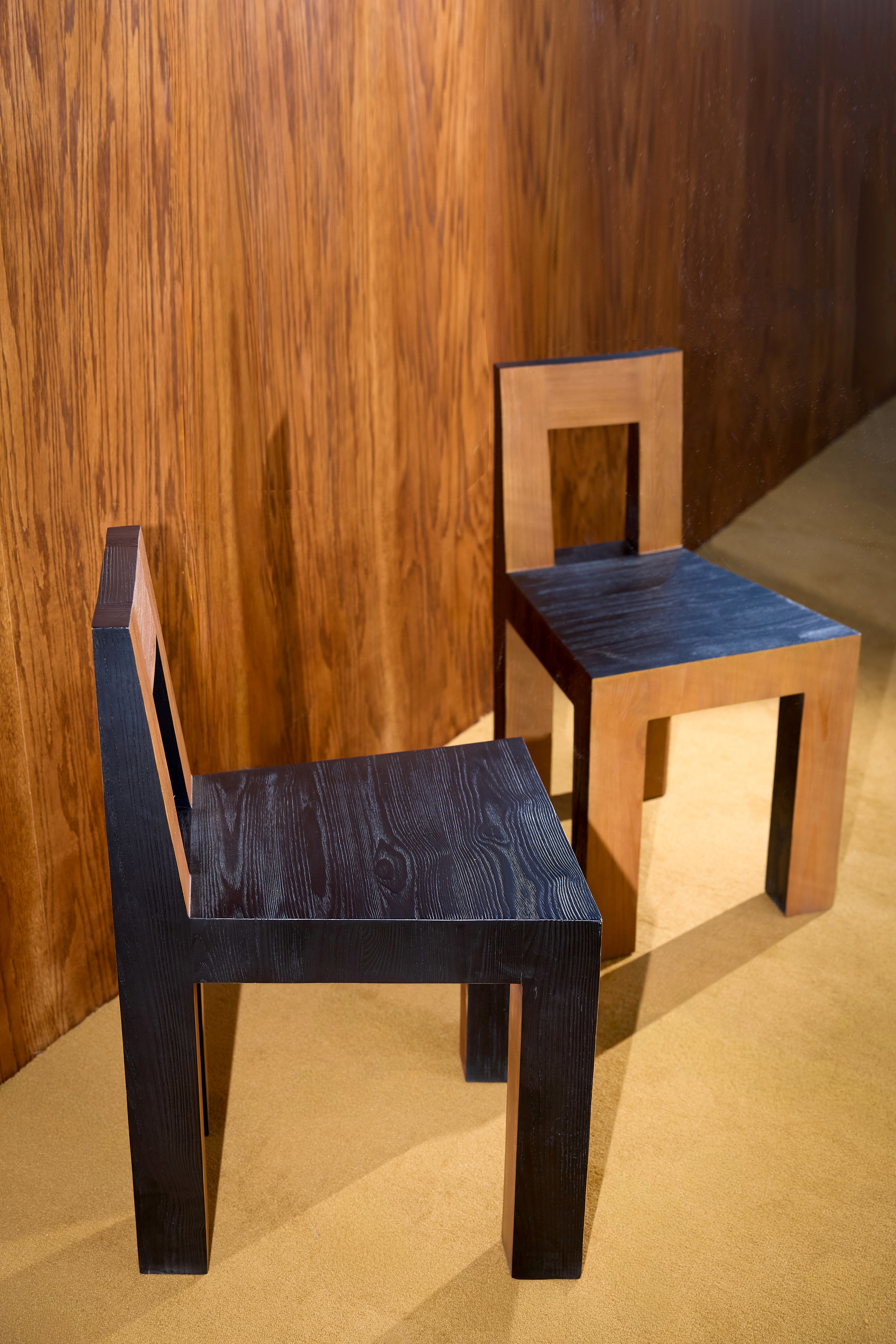 Geometrical wooden chairs in natural and black-painted finish.
