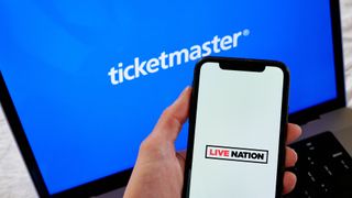 Ticketmaster logo pictured on a laptop screen with Live Nation logo on a smartphone screen in foreground.