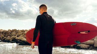 Person surfing/paddle boarding wearing wetsuit
