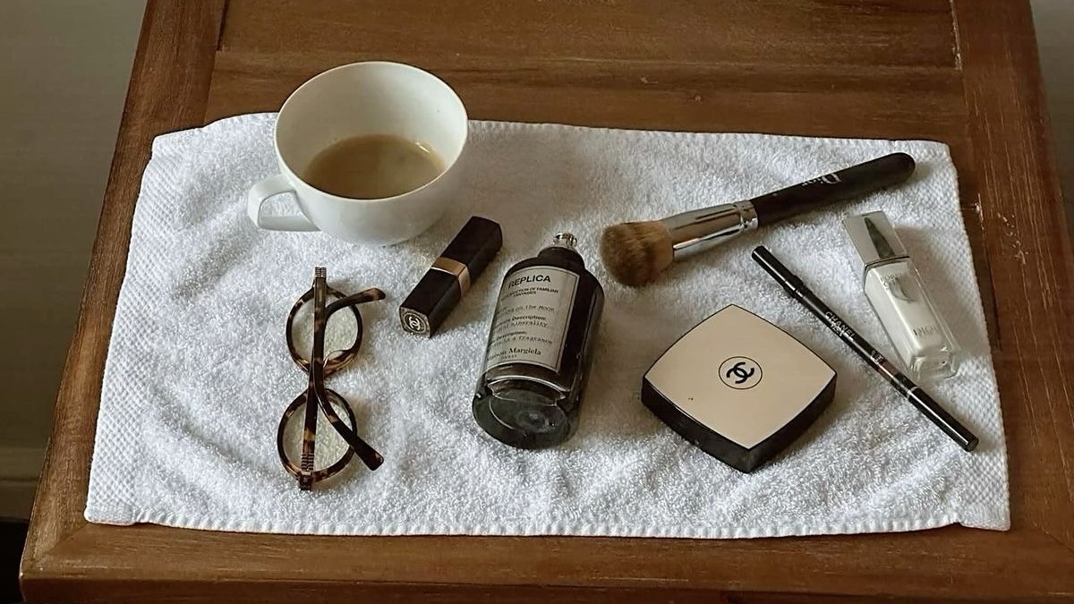 Photo of perfume, makeup, glasses, and coffee laid out on a table
