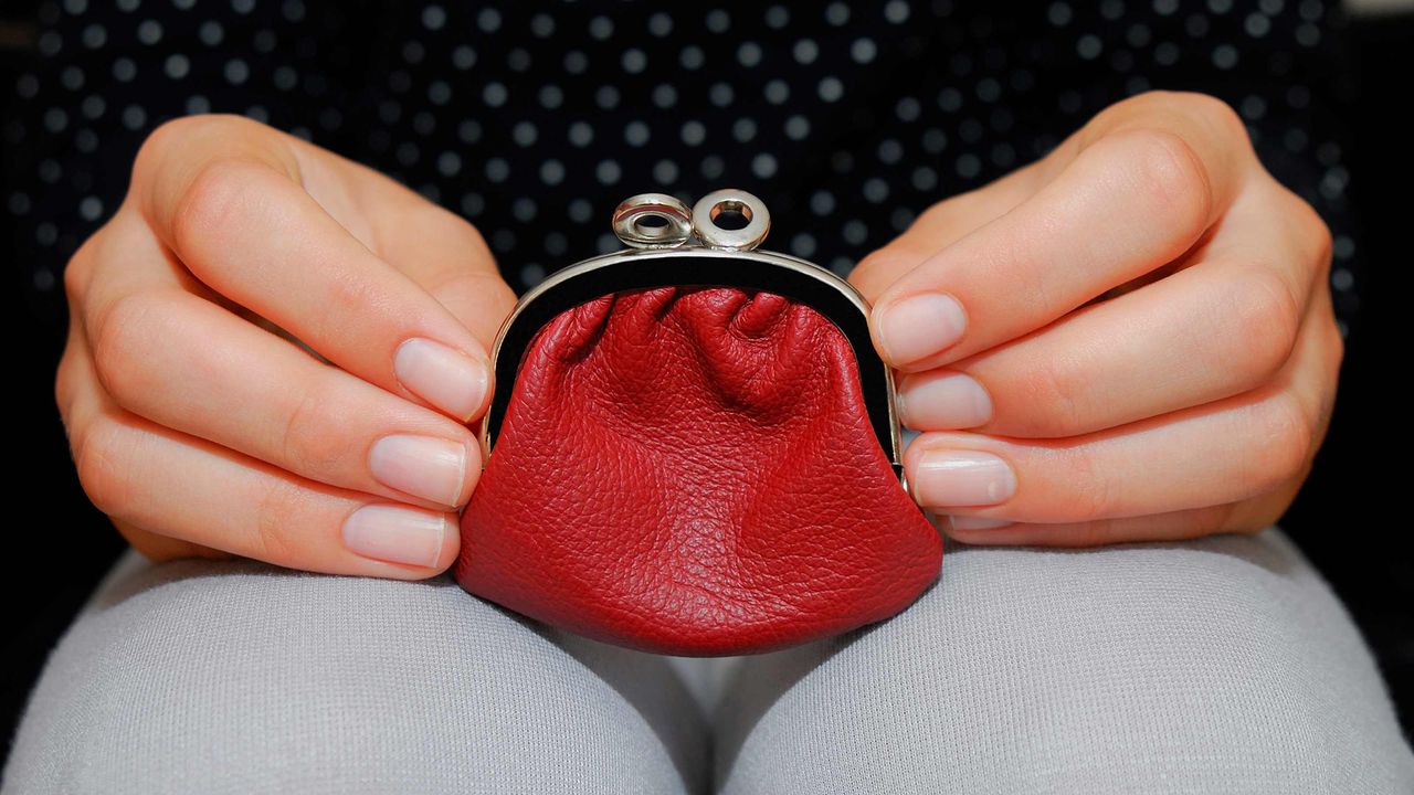 A small red change purse on a woman&amp;#039;s lap.