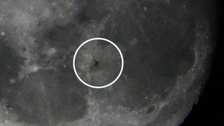 a shadow of a space station on the face of the moon. a circle surrounds the space station