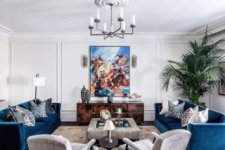 living room with blue sofas and gray chairs and modern artwork