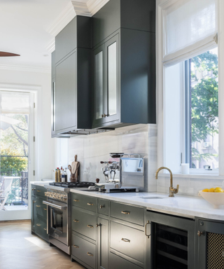 A kitchen with gray cabinets, an espresso maker and a range hood