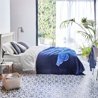 bedroom flooring ideas, blue and white bedroom with blue and white pattered tiles, white voile curtains, plants, blue throw on bed, white basket