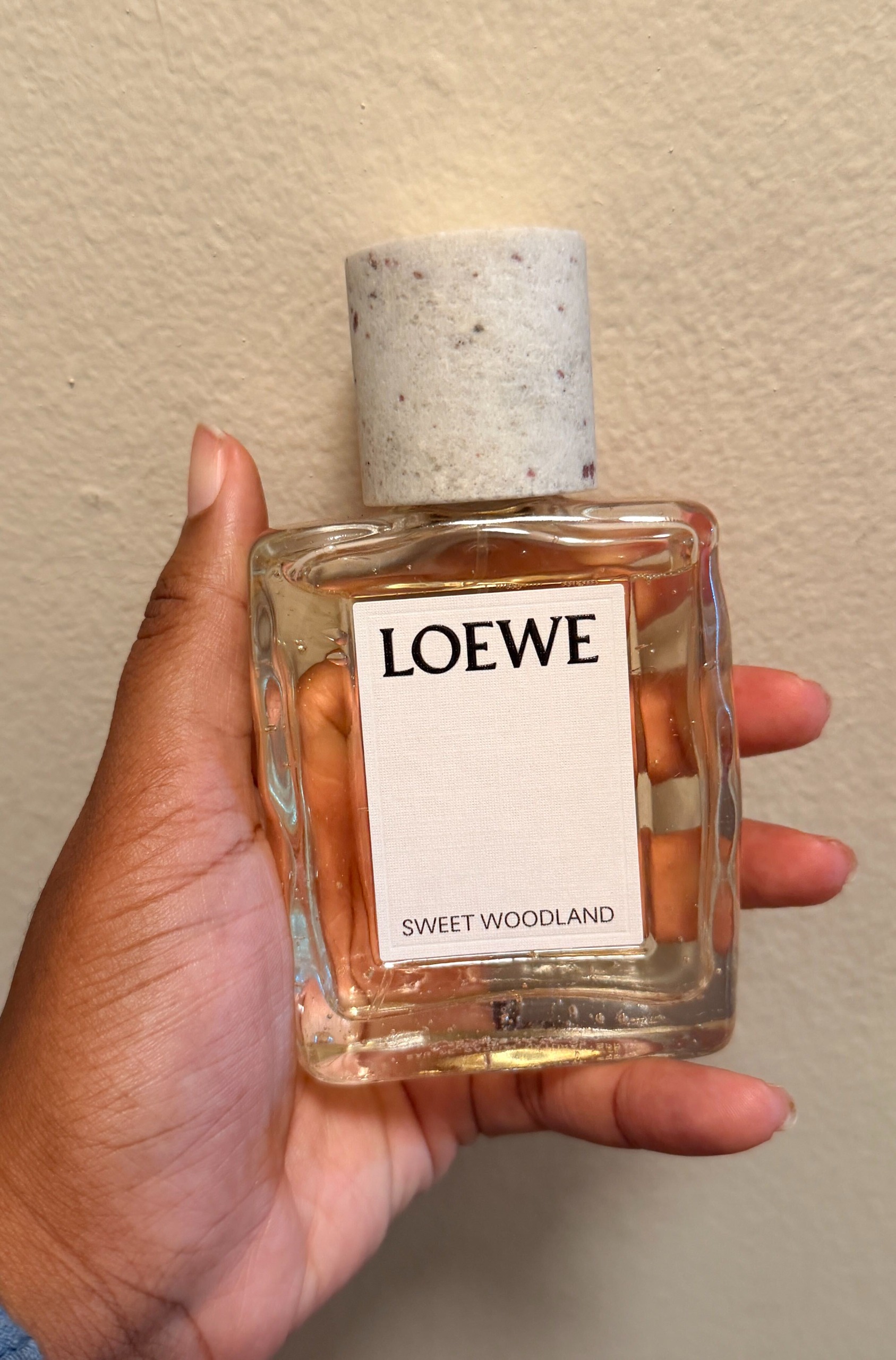 An Image of Ariel holding Loewe Sweet Woodland Perfume.