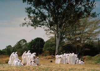 A group of people in a field wearing white religious clothing during the day