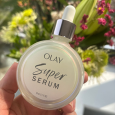 a hand holding a bottle of olay super serum