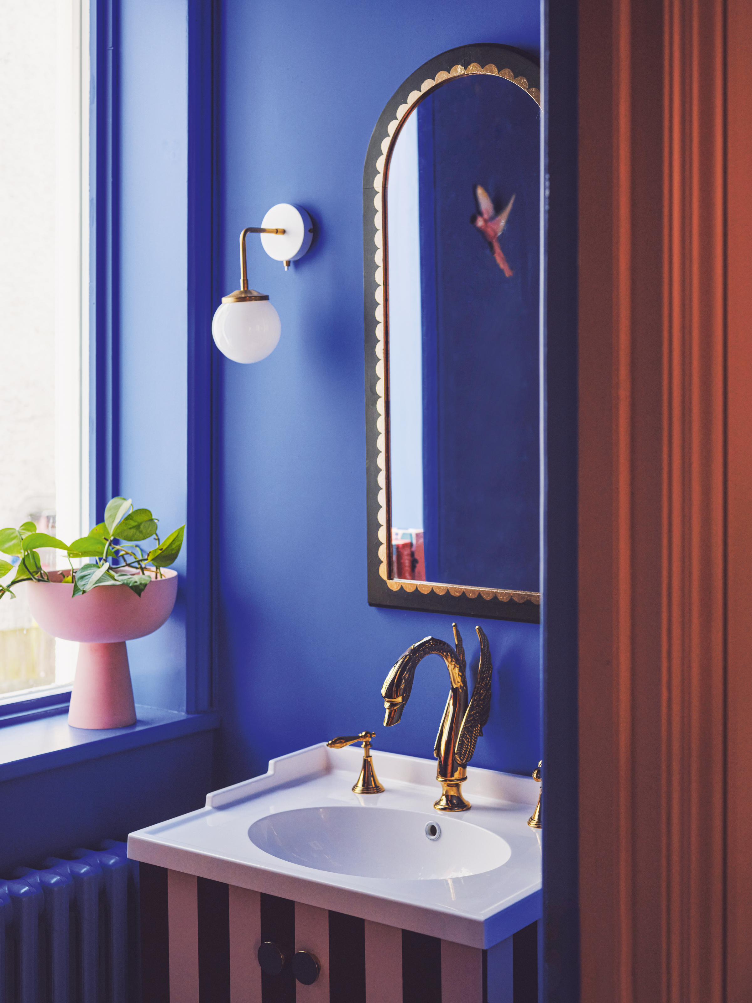 Cobalt blue powder room with black and white striped painted sink and arched mirror