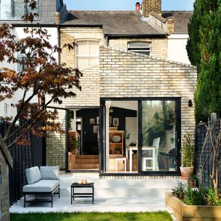 Exterior shot of extended kitchen with sloped roof and terraced patio