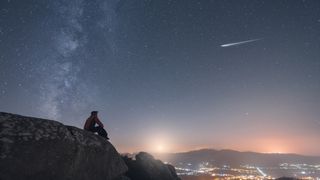 A man watching a shoothing star, the the milky way and the moonset