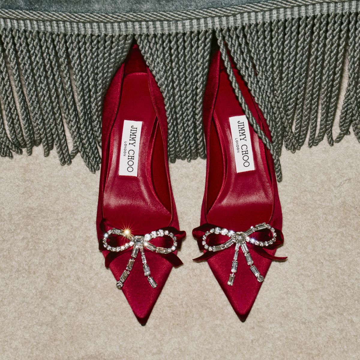 a pair of red satin jimmy choo heels with diamante bows