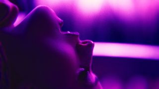 a woman leans her head back and gasps in a purple lit still from the movie touch me