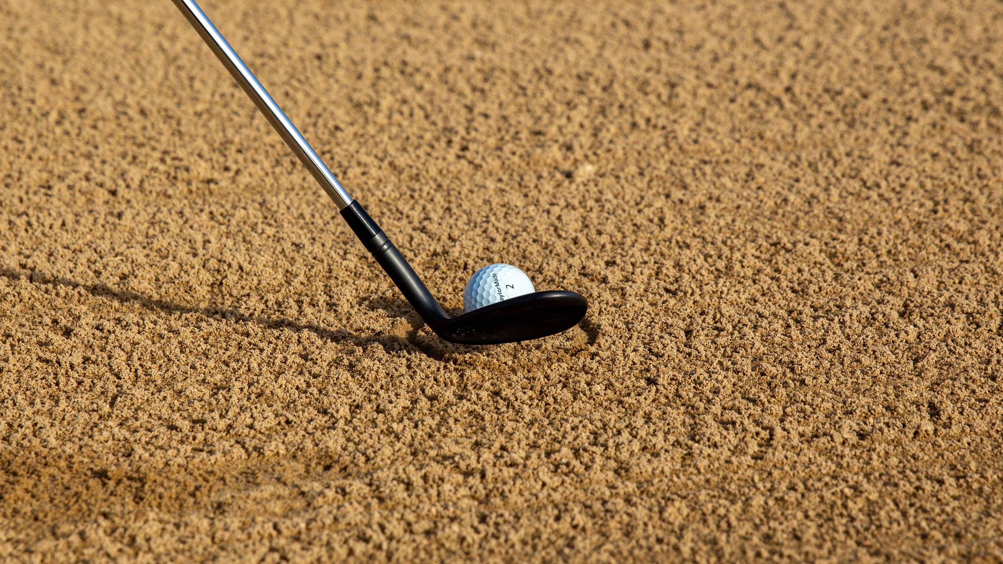 Golf club behind the ball in a bunker