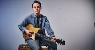 Chris Buck sits on a vintage Fender tube amp with his goldtop Yamaha Revstar.