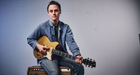 Chris Buck sits on a vintage Fender tube amp with his goldtop Yamaha Revstar.